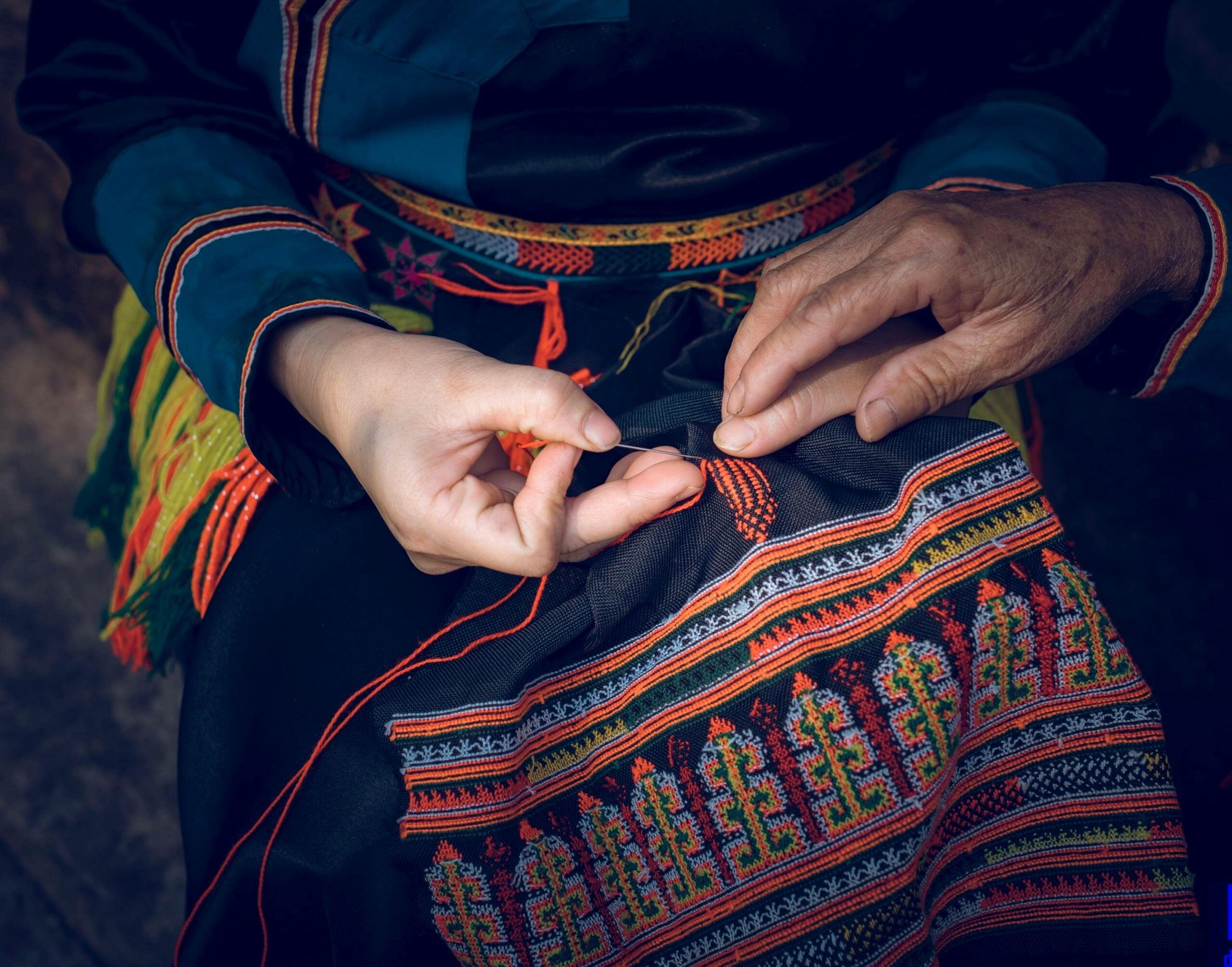 Close-up of hands creating traditional embroidery with vibrant colors.